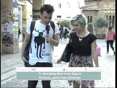 Ο Δημήτρης με μικρόφωνο του MAD παίρνει συνέντευξη από μια κοπέλα στον δρόμο.