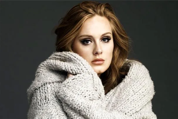 Η Adele ποζάρει τυλιγμένη με μια γκρι πλεκτή ζακέτα.