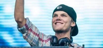 Ο Avicii χαμογελάει με το χέρι υψωμένο σε συναυλία.