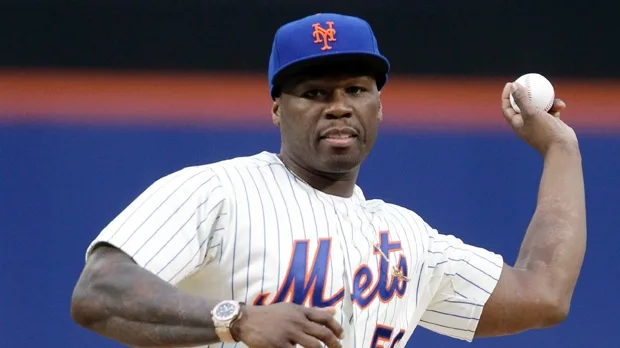 Ο 50 Cent με στολή των New York Mets ετοιμάζεται να ρίξει μια μπάλα μπέιζμπολ.