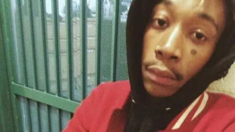 Ο Wiz Khalifa βγάζει selfie φορώντας μαύρη κουκούλα και κόκκινη ζακέτα.