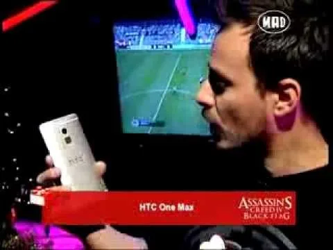 Παρουσιαστής δείχνει το smartphone HTC One Max σε τηλεοπτική εκπομπή.