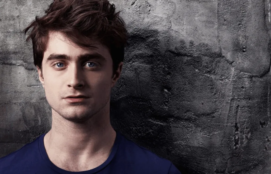 Ο Daniel Radcliffe ποζάρει μπροστά από έναν γκρίζο τοίχο.