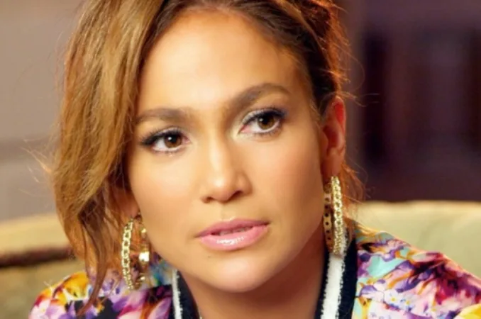 Κοντινό πλάνο της Jennifer Lopez με χρυσούς κρίκους και φλοράλ ρούχο.