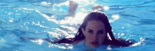 Η Lana Del Rey κολυμπάει σε μια πισίνα με γαλάζια νερά.