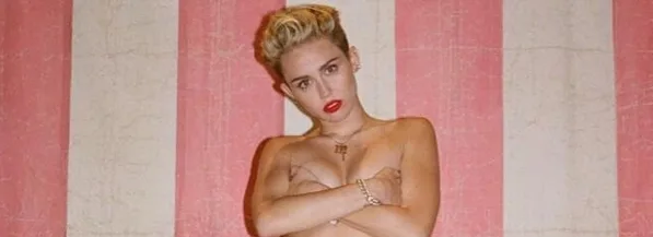 Η Miley Cyrus ποζάρει μπροστά από φόντο με ροζ και λευκές ρίγες.