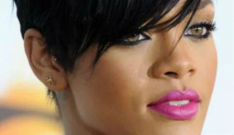 Κοντινό πλάνο της Rihanna με κοντό μαύρο μαλλί και έντονο ροζ κραγιόν.