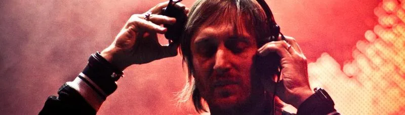 Ο David Guetta με ακουστικά σε κόκκινο φόντο.