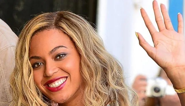 Η Beyonce χαμογελά και χαιρετά με το χέρι της.