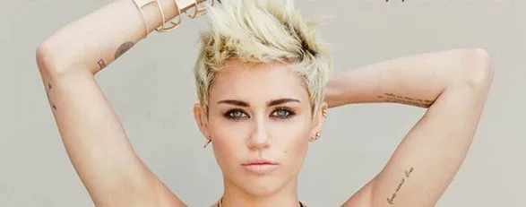Η Miley Cyrus με κοντό ξανθό μαλλί και τατουάζ στα χέρια.