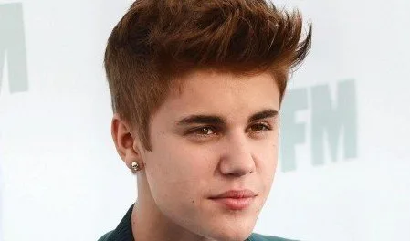 Ο Justin Bieber σε κοντινό πλάνο με καστανά μαλλιά και σκουλαρίκι.
