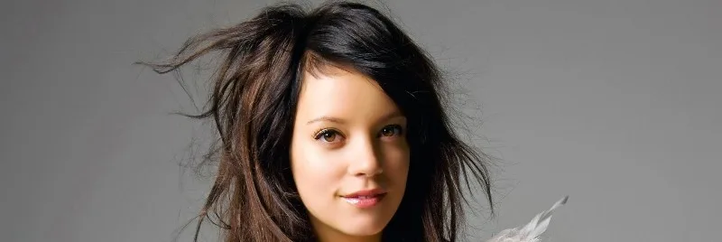 Η Lily Allen με ανακατεμένα μαλλιά σε γκρίζο φόντο.