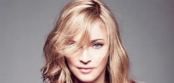 Κοντινό πορτρέτο της Madonna με ξανθά μαλλιά σε γκρίζο φόντο.