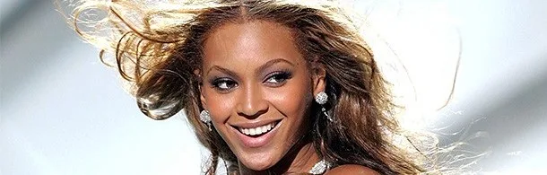 Η Beyonce χαμογελάει με τα μαλλιά της να ανεμίζουν.
