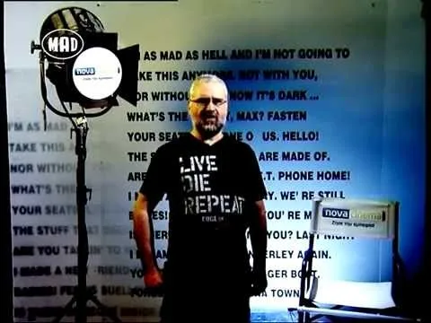 Ο Ηλίας Φραγκούλης σε τηλεοπτικό πλατό με κινηματογραφικό φόντο.