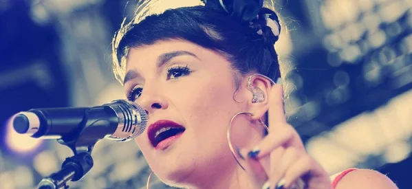 Η Jessie Ware τραγουδάει σε μικρόφωνο κατά τη διάρκεια συναυλίας.