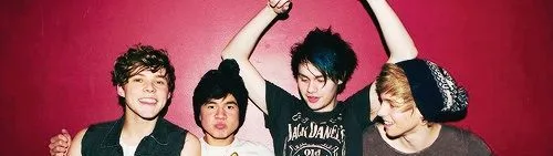 Τα μέλη του συγκροτήματος 5 Seconds Of Summer ποζάρουν μπροστά από κόκκινο τοίχο.