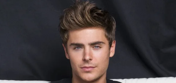 Ο Zac Efron σε κοντινό πλάνο με καστανά μαλλιά και γαλάζια μάτια.