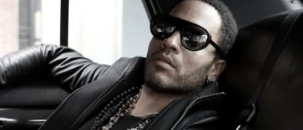 Ο Lenny Kravitz με μαύρα γυαλιά ηλίου και δερμάτινο τζάκετ στο πίσω κάθισμα αυτοκινήτου.