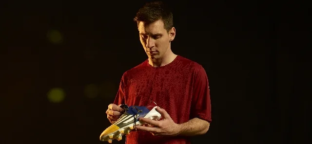 Ο Leo Messi κρατάει ένα ποδοσφαιρικό παπούτσι adidas adizero f50.