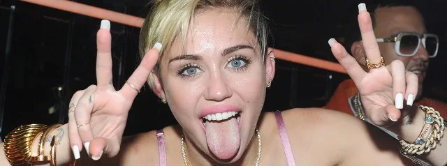 Η Miley Cyrus βγάζει τη γλώσσα της κάνοντας το σήμα της ειρήνης.