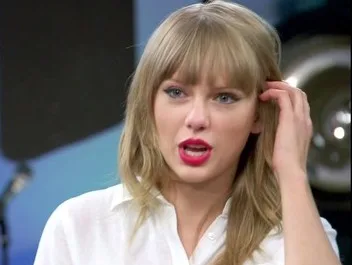 Η Taylor Swift με ξανθά μαλλιά, αφέλειες και κόκκινο κραγιόν.