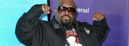 Ο CeeLo Green ποζάρει με υψωμένες γροθιές μπροστά από φόντο NBCUniversal.
