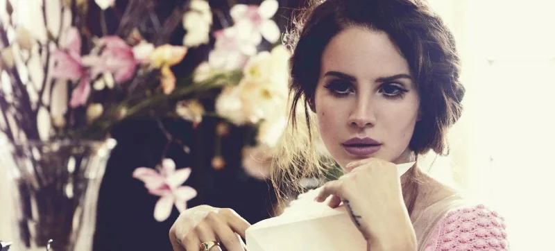 Η Lana Del Rey σε κοντινό πλάνο με λουλούδια στο φόντο