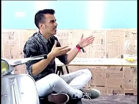 Ο Δημήτρης Ουγγαρέζος σε στούντιο εκπομπής με φόντο εφημερίδες.