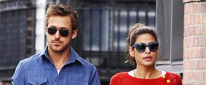 Ο Ryan Gosling και η Eva Mendes περπατούν μαζί φορώντας γυαλιά ηλίου.