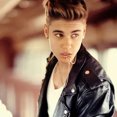 Ο Justin Bieber με μαύρο δερμάτινο μπουφάν και χρυσό σταυρό στο στόμα.