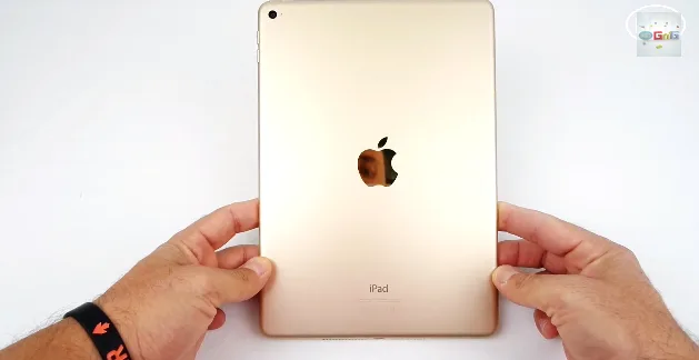 Το πίσω μέρος ενός χρυσού Apple iPad Air 2 που κρατούν δύο χέρια.