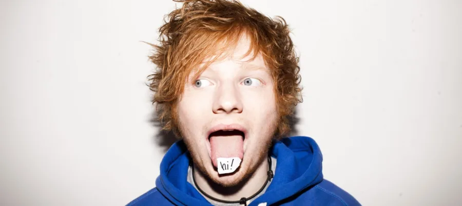 Ο Ed Sheeran με την γλώσσα έξω και ένα χαρτάκι που γράφει hi!