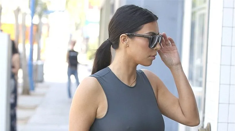 Η Kim Kardashian με γκρι αμάνικο φόρεμα και γυαλιά ηλίου στο δρόμο.