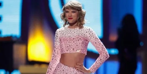 Η Taylor Swift σε σκηνή με ροζ αστραφτερό crop top.