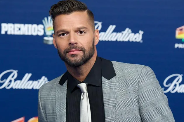 Ο Ricky Martin με γκρι κοστούμι και μαύρο πουκάμισο σε εκδήλωση.