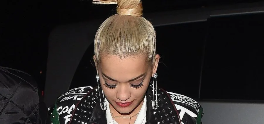Κοντινό πλάνο της Rita Ora με ξανθά μαλλιά πιασμένα κότσο και σκουλαρίκια παραμάνες.