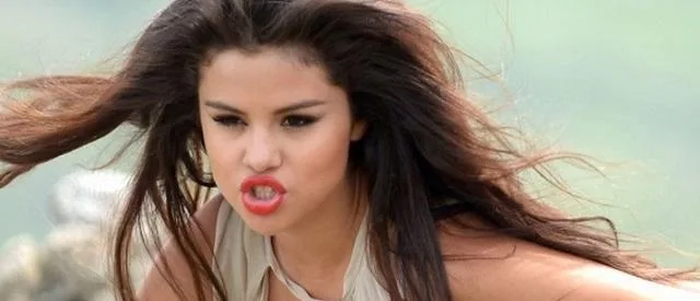 Η Selena Gomez με έντονη έκφραση προσώπου και κόκκινο κραγιόν.