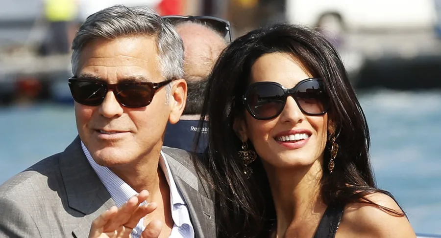Ο George Clooney και η Amal Alamuddin με γυαλιά ηλίου σε εξωτερικό χώρο.