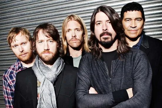 Το συγκρότημα Foo Fighters ποζάρει μπροστά από μεταλλικό ρολό.