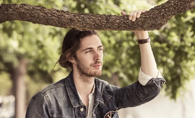 Ο Hozier ποζάρει κάτω από ένα κλαδί δέντρου.