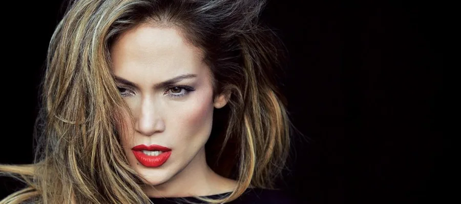 Κοντινό πορτρέτο της Jennifer Lopez με έντονο κόκκινο κραγιόν και ξανθές ανταύγειες.
