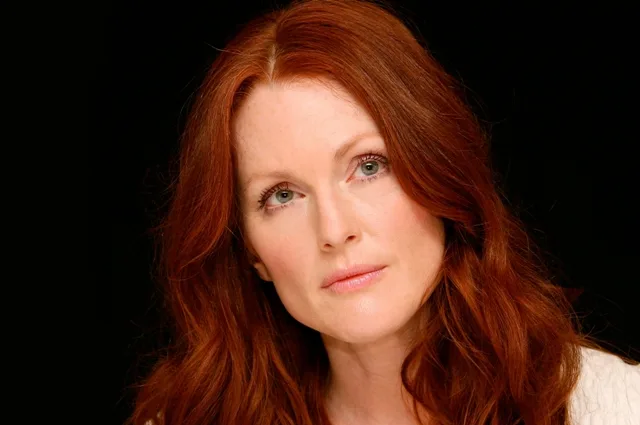 Κοντινό πορτρέτο της Julianne Moore με κόκκινα μαλλιά σε μαύρο φόντο.
