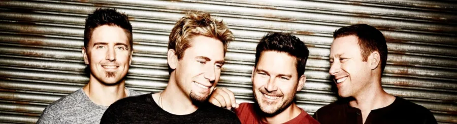 Το συγκρότημα Nickelback ποζάρει μπροστά από μεταλλικό φόντο.