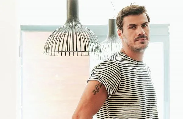 Ο Άκης Πετρετζίκης ποζάρει σε εσωτερικό χώρο.