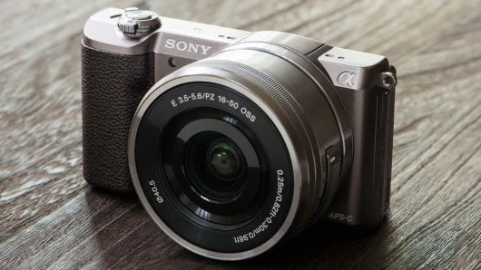Φωτογραφική μηχανή Sony Alpha 5100 με φακό 16-50mm πάνω σε ξύλινη επιφάνεια.