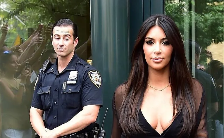 Η Kim Kardashian περπατάει μπροστά από έναν αστυνομικό.