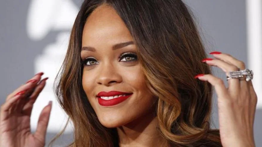 Κοντινό πλάνο της Rihanna με κόκκινο κραγιόν και μακριά καστανά μαλλιά.