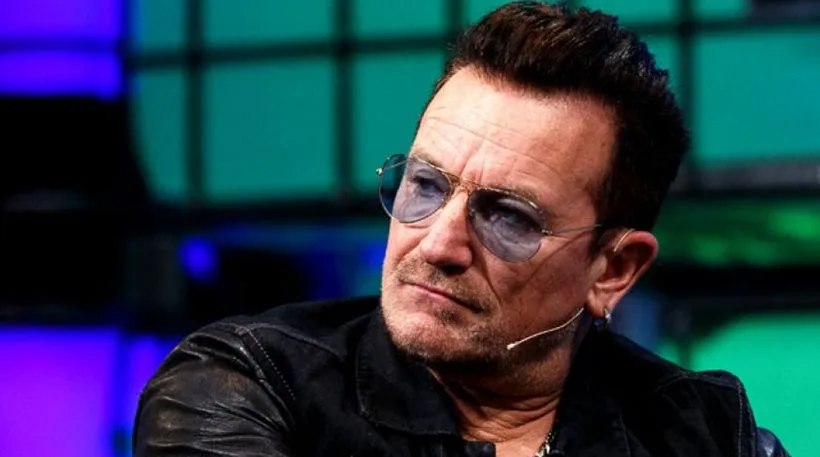 Ο Bono των U2 με γυαλιά ηλίου και μαύρο τζάκετ.