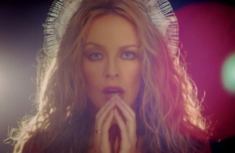 Η Kylie Minogue με εντυπωσιακό headpiece και τα χέρια σε στάση προσευχής.